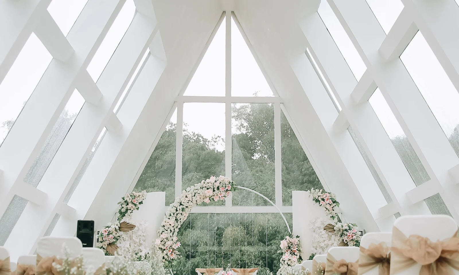 Wedding ceremony aisle with a floral arch, chairs and daylight