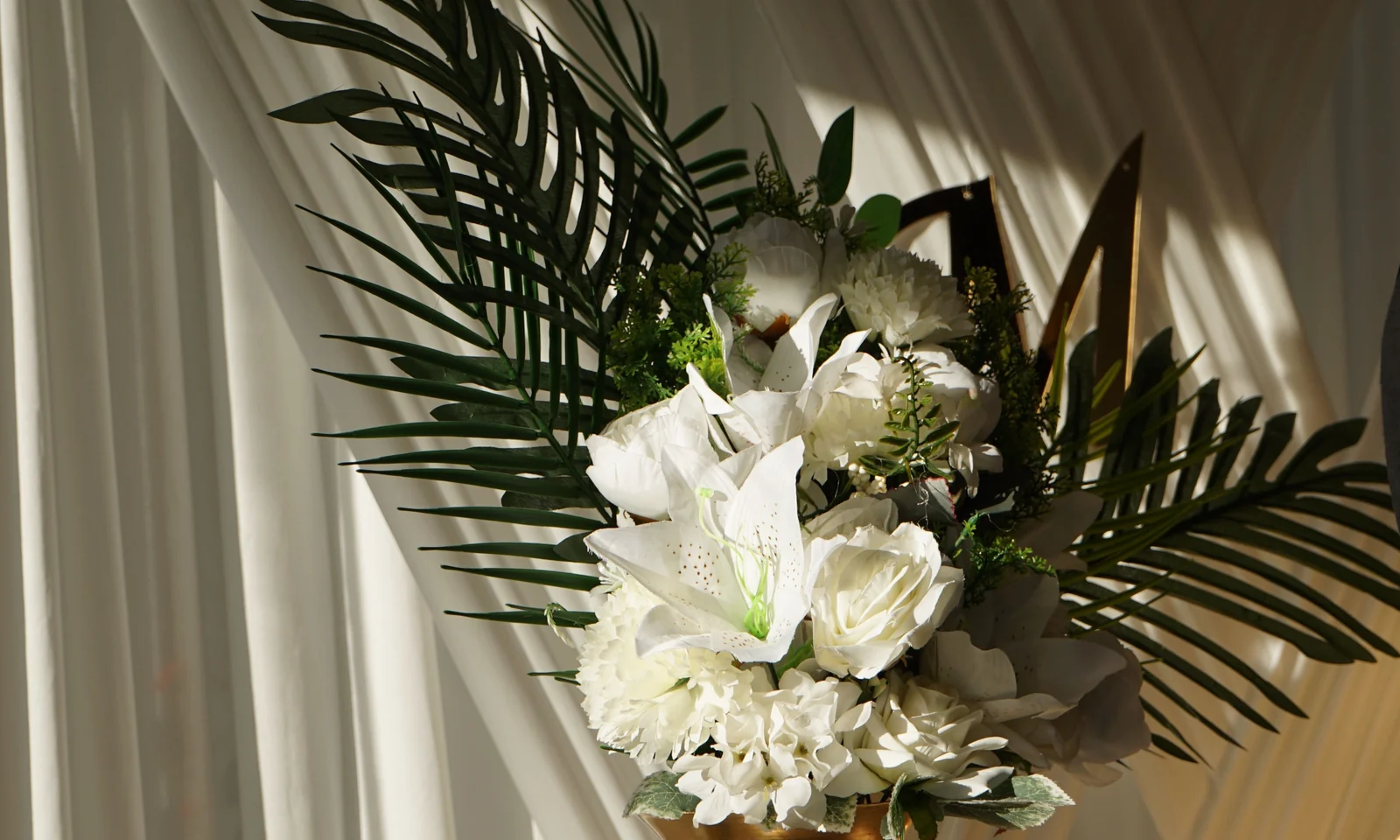 Wedding floral display with drapery and a decorative gold vase