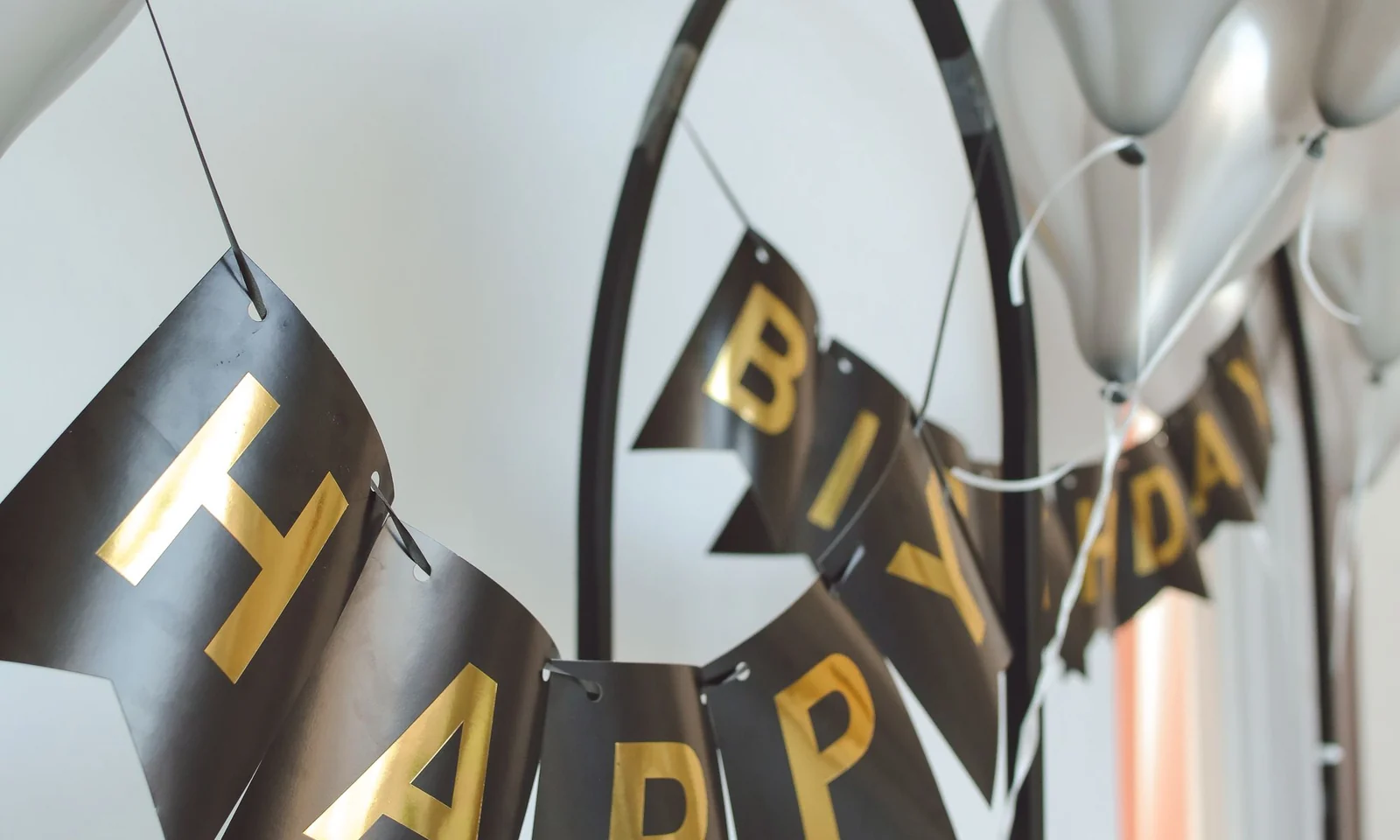 Black and gold happy birthday banner installed with silver balloons