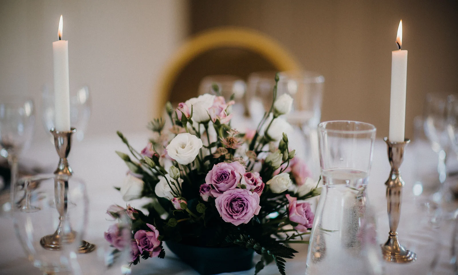 Wedding table centrepiece with flowers, candles, glassware and place settings