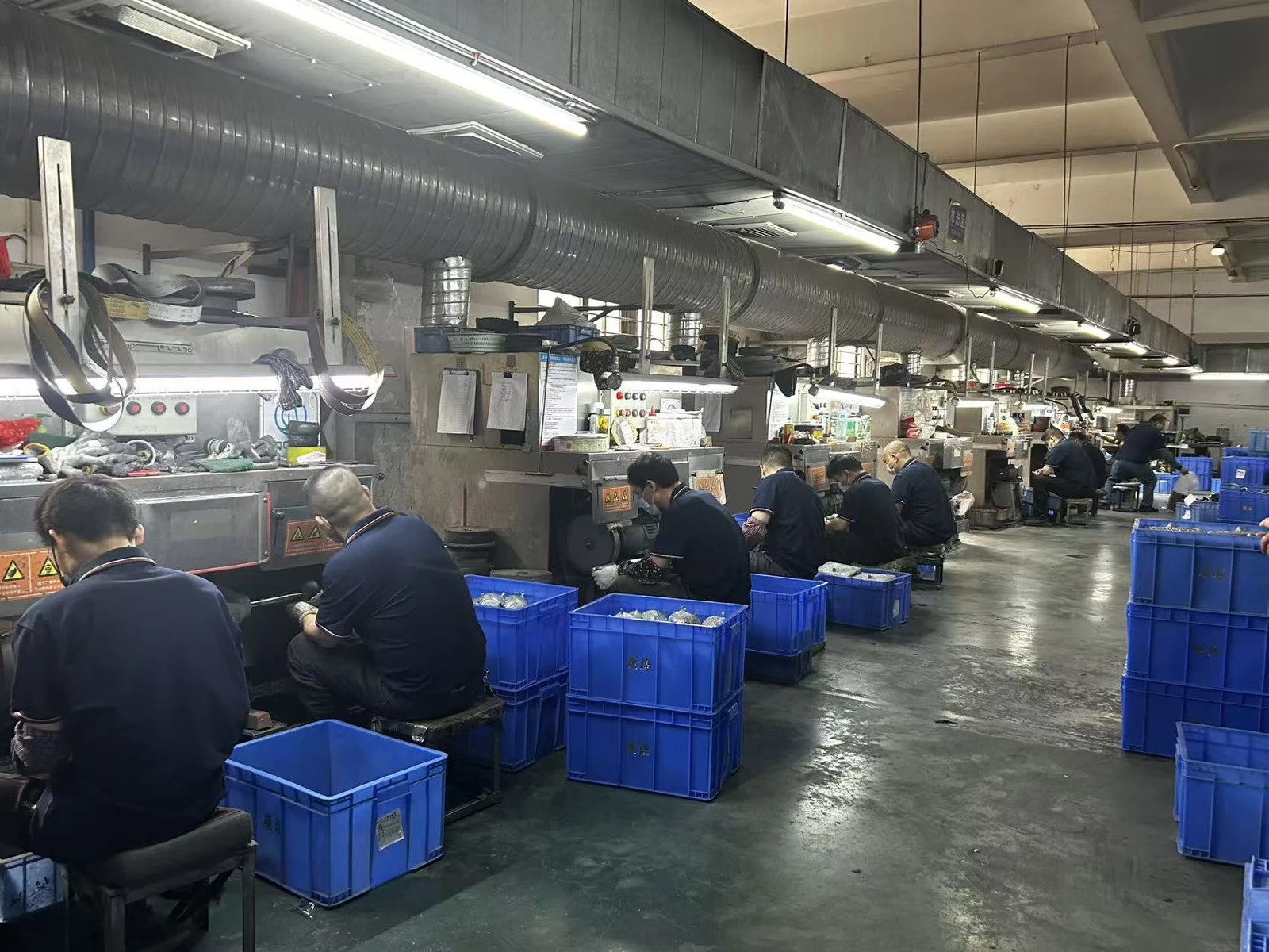 Workshop operators working along a metal finishing production line